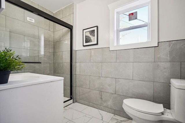 full bathroom with tile walls, toilet, marble finish floor, and a shower stall