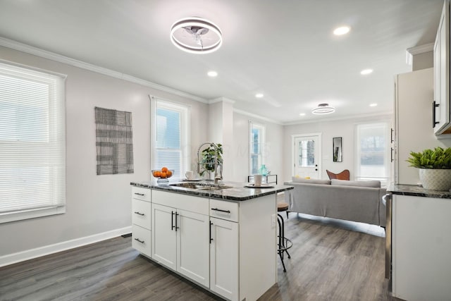 kitchen featuring a center island with sink, dark wood finished floors, open floor plan, and crown molding