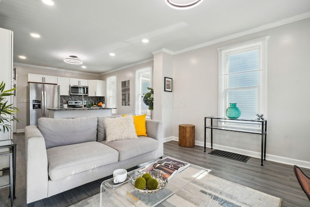 living room featuring baseboards, a healthy amount of sunlight, dark wood finished floors, and crown molding