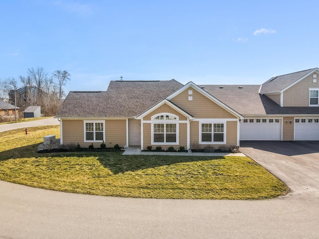 view of front facade featuring aphalt driveway, a front lawn, and a shingled roof