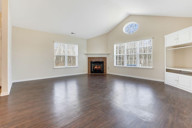 unfurnished living room featuring lofted ceiling, dark wood-type flooring, and a wealth of natural light