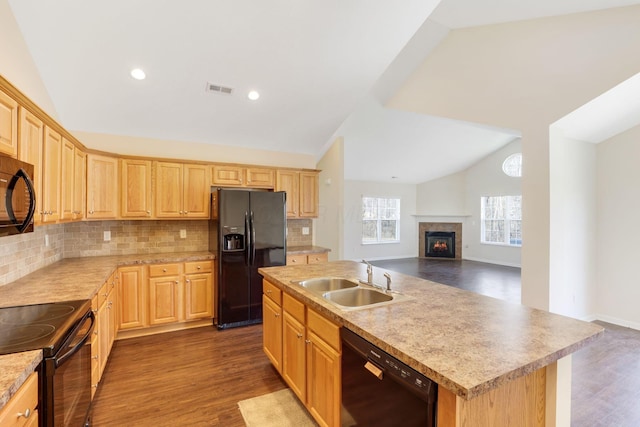 kitchen featuring light brown cabinets, a sink, black appliances, vaulted ceiling, and open floor plan