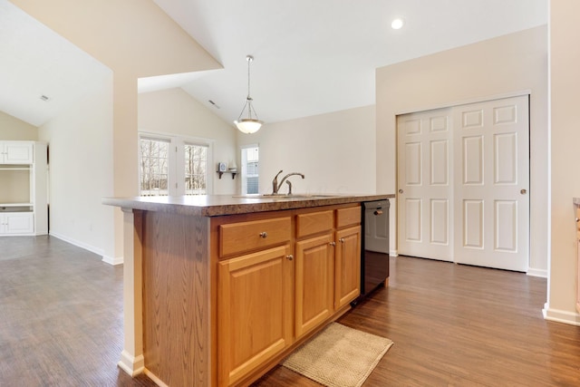 kitchen with dishwasher, vaulted ceiling, wood finished floors, and a sink