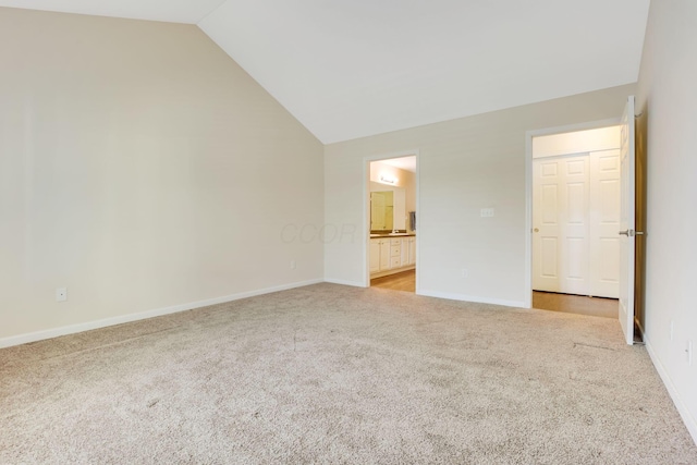 unfurnished bedroom featuring baseboards, lofted ceiling, carpet, and connected bathroom