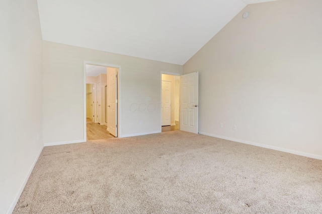 unfurnished bedroom with connected bathroom, high vaulted ceiling, baseboards, and carpet floors