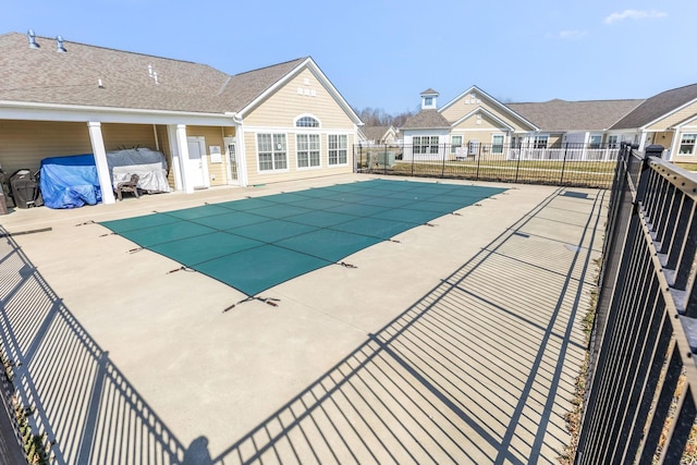 community pool with a patio area and fence