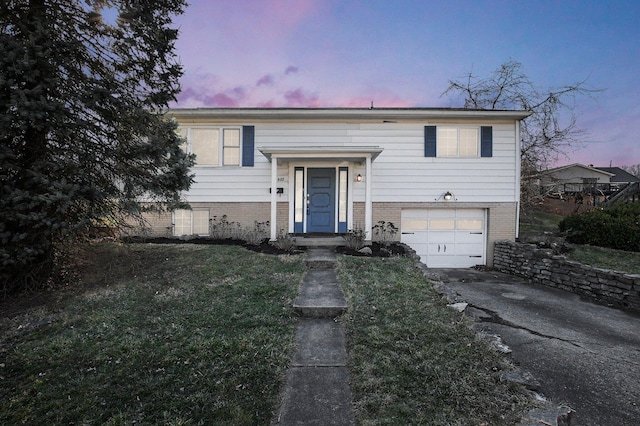 split foyer home with driveway, brick siding, and an attached garage