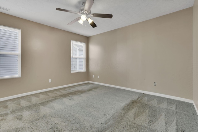 carpeted empty room with visible vents, a textured ceiling, baseboards, and a ceiling fan