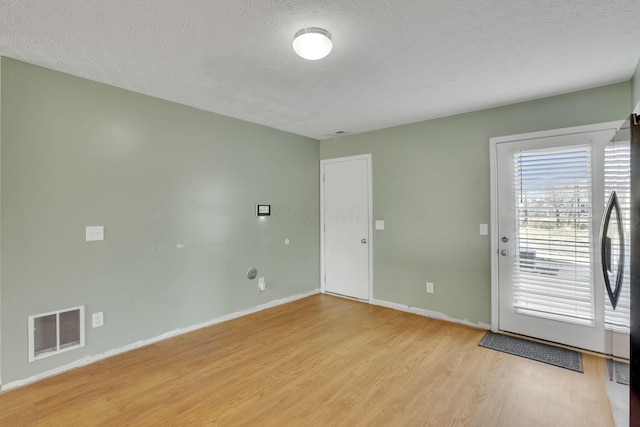 interior space featuring light wood-style flooring, baseboards, visible vents, and a textured ceiling