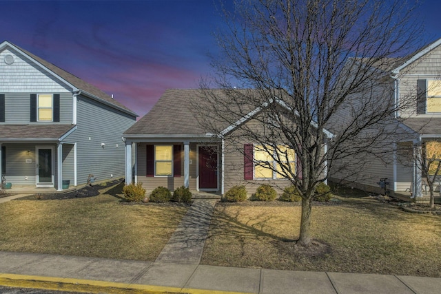 view of front facade featuring a shingled roof and a front lawn