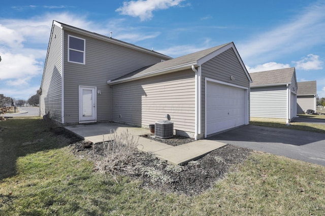 back of property with central air condition unit, a lawn, driveway, and a garage