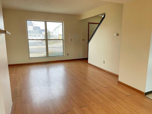 unfurnished room with baseboards and light wood-style floors