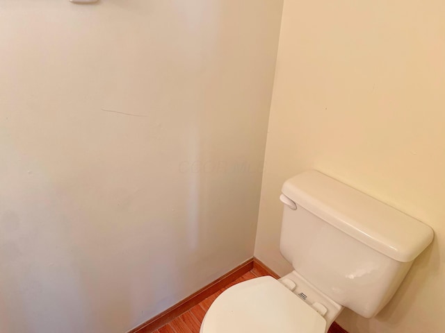 bathroom with toilet, wood finished floors, and baseboards