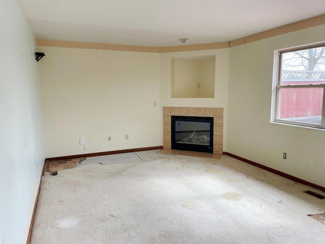 unfurnished living room featuring carpet, a fireplace, visible vents, and baseboards