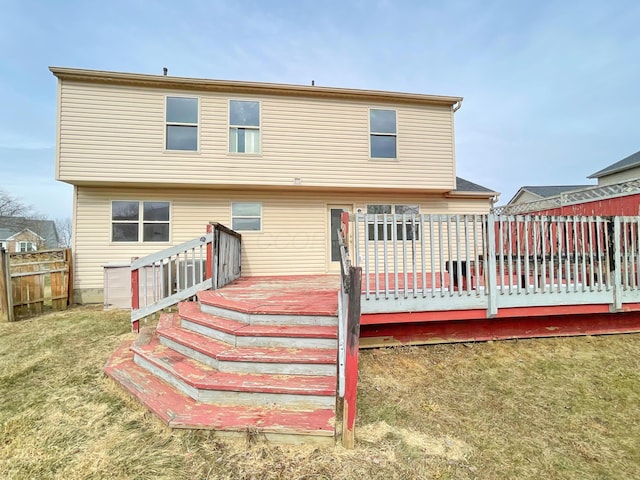 back of property with a yard, a deck, and fence