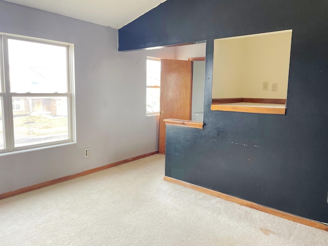 unfurnished room featuring plenty of natural light, baseboards, carpet, and vaulted ceiling