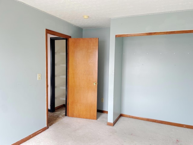 unfurnished bedroom with a closet, baseboards, a textured ceiling, and carpet floors