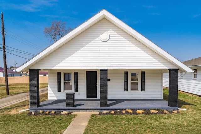 bungalow-style home with covered porch, a front yard, and fence