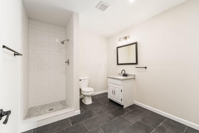 bathroom with visible vents, toilet, a tile shower, baseboards, and vanity