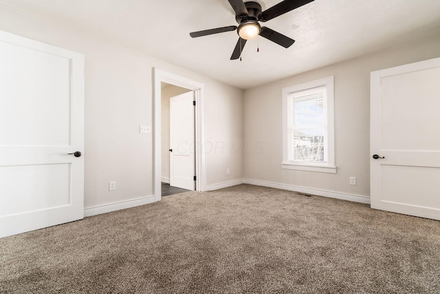 unfurnished bedroom featuring a ceiling fan, visible vents, carpet, and baseboards