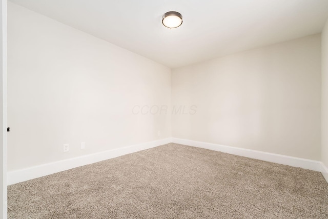 carpeted spare room featuring baseboards