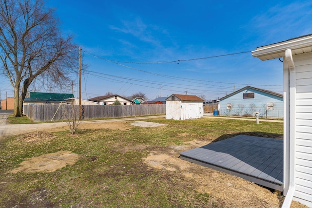 view of yard with a storage shed, fence, an outdoor structure, and a wooden deck