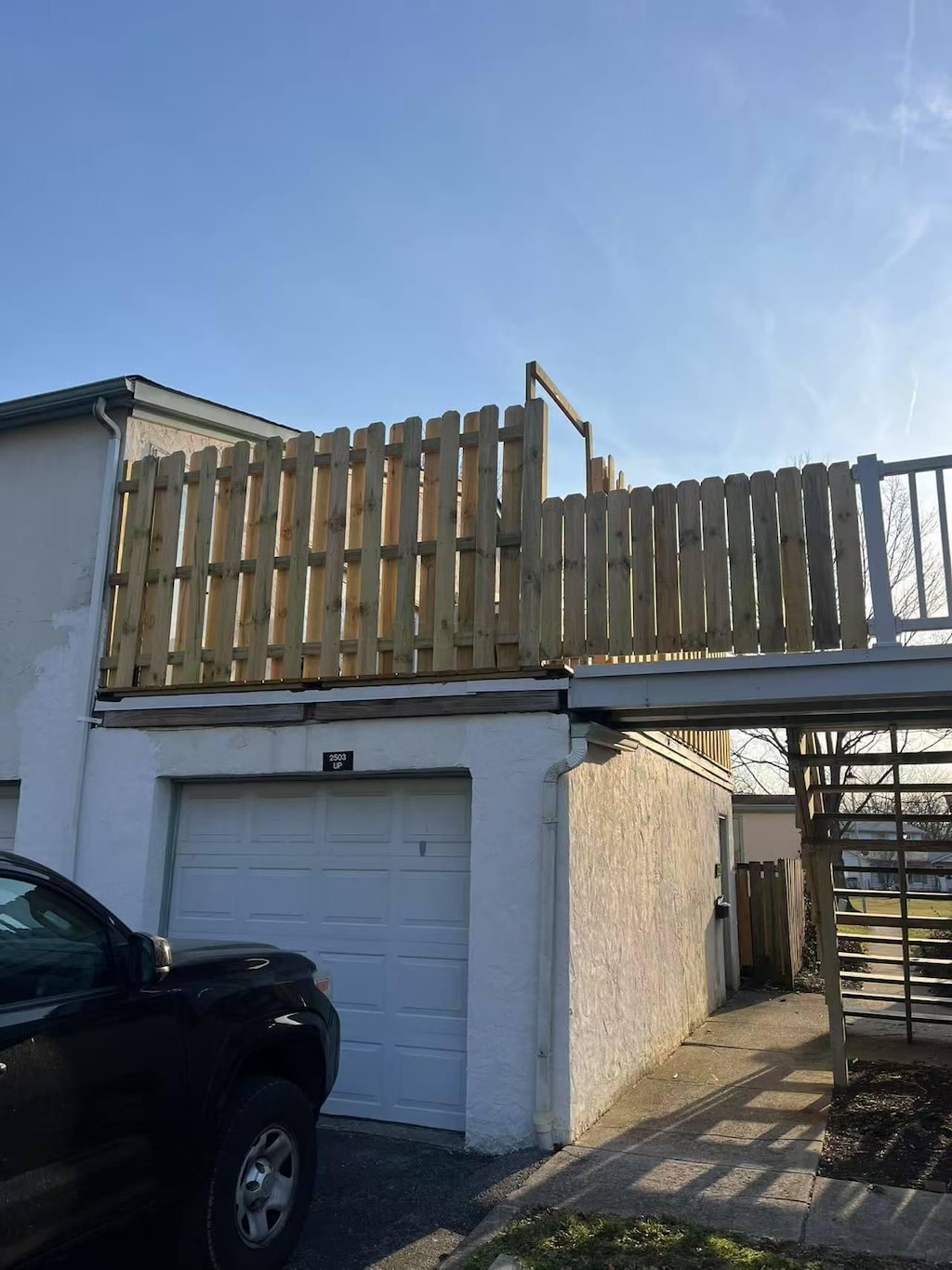 view of side of home with stucco siding, a garage, and fence