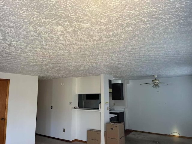 unfurnished living room with a ceiling fan and a textured ceiling