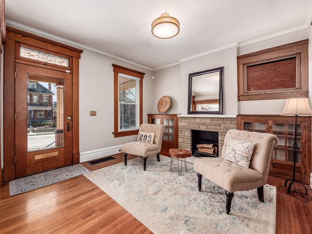 living area featuring a healthy amount of sunlight, wood finished floors, and crown molding