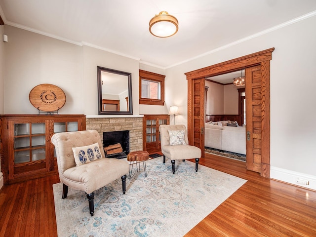 sitting room with a fireplace, crown molding, wood finished floors, and baseboards