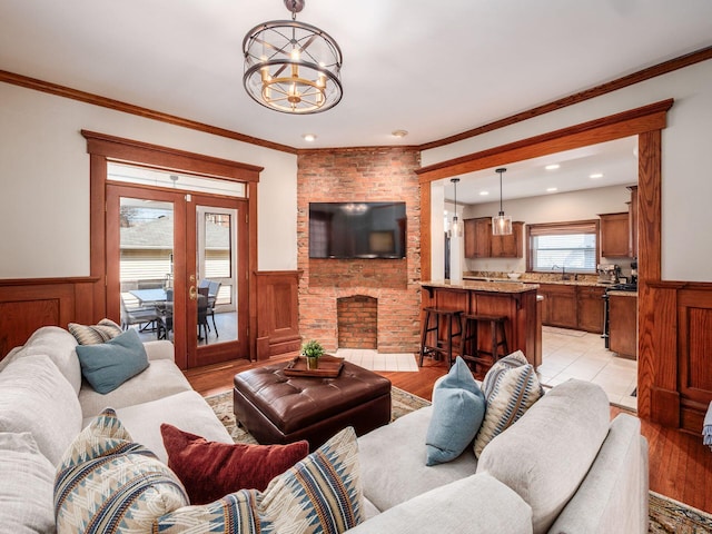 living area featuring a chandelier, ornamental molding, wainscoting, and light wood finished floors