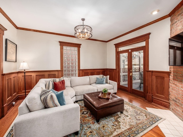 living area with a notable chandelier, a wainscoted wall, light wood-style flooring, and french doors