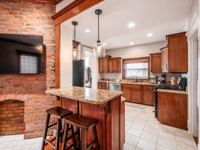 kitchen with a breakfast bar area, appliances with stainless steel finishes, a peninsula, brown cabinetry, and a sink