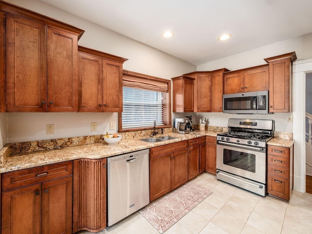 kitchen featuring light stone countertops, recessed lighting, brown cabinetry, stainless steel appliances, and a sink