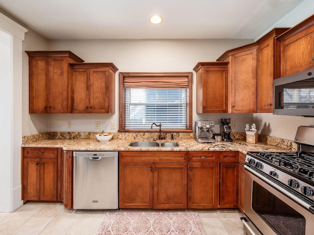 kitchen with brown cabinets, a sink, light stone counters, recessed lighting, and stainless steel appliances