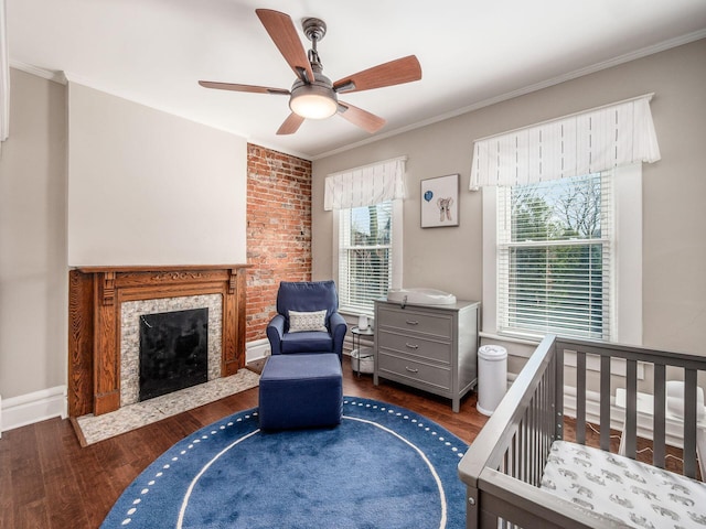 bedroom featuring a fireplace with flush hearth, wood finished floors, baseboards, and ornamental molding