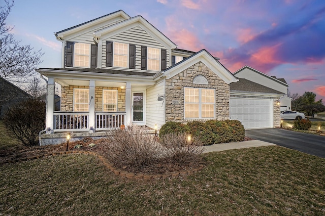 traditional-style house featuring a garage, stone siding, a porch, and driveway