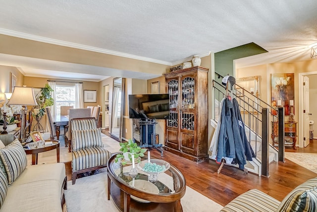 living room with crown molding, wood finished floors, baseboards, and a textured ceiling