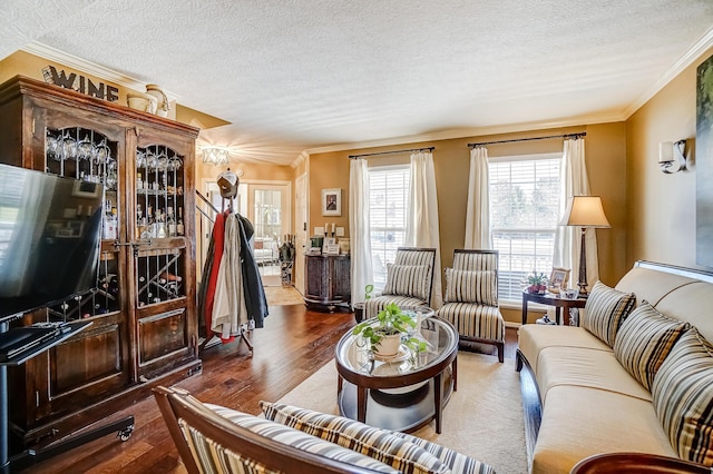 living area with ornamental molding, a textured ceiling, and wood finished floors