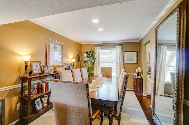 dining space with a textured ceiling, wood finished floors, baseboards, and ornamental molding