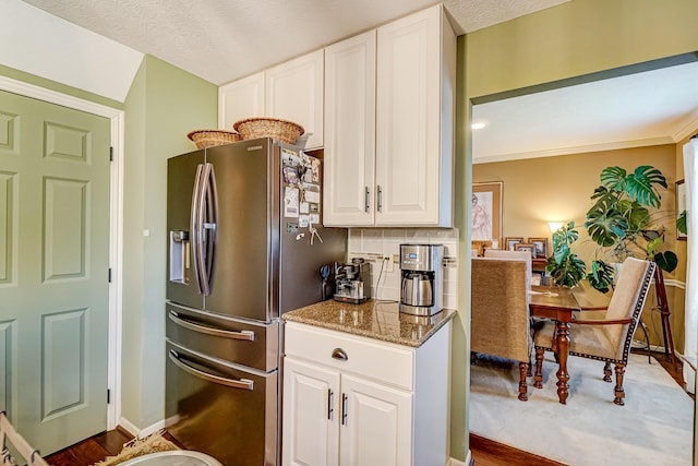 kitchen with white cabinetry, stainless steel fridge with ice dispenser, tasteful backsplash, and stone counters