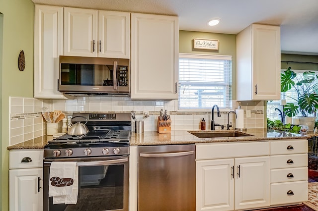 kitchen with white cabinets, light stone countertops, appliances with stainless steel finishes, and a sink