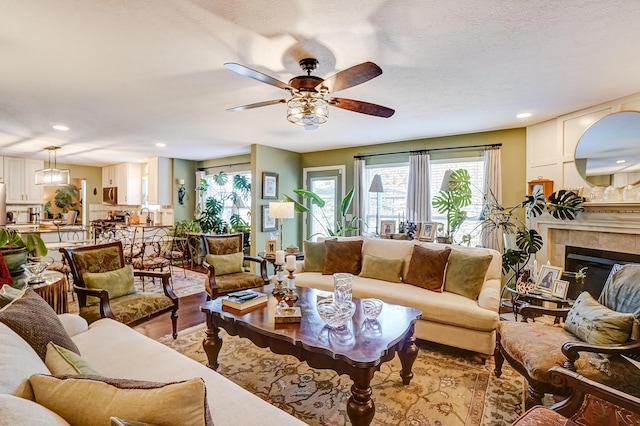 living room with recessed lighting, a fireplace, light wood-style floors, and ceiling fan