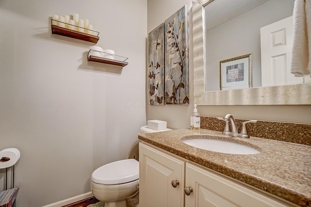 bathroom with vanity, toilet, and baseboards