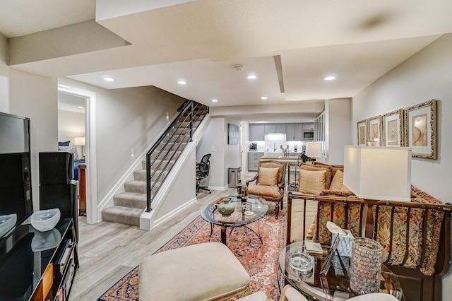 living room with recessed lighting, light wood-style flooring, stairs, and baseboards