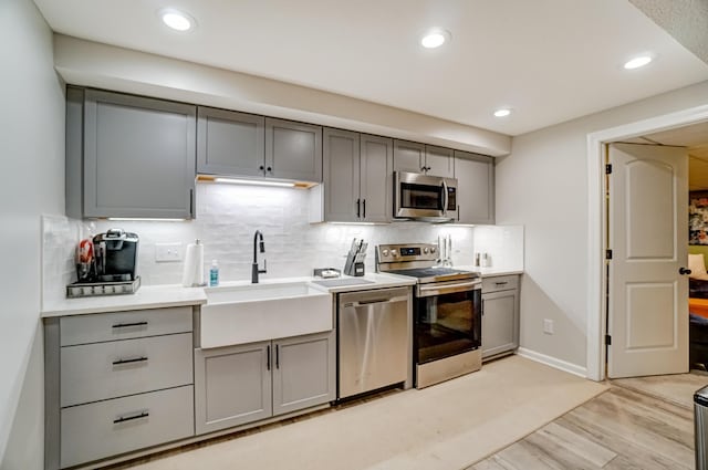 kitchen with a sink, stainless steel appliances, and gray cabinets