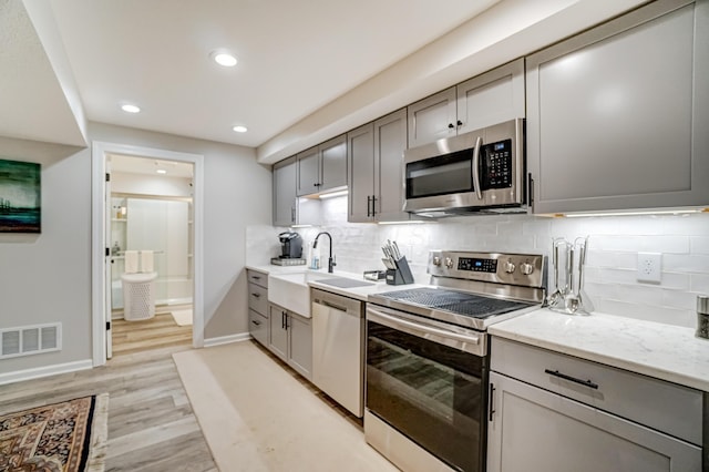 kitchen featuring gray cabinets, visible vents, appliances with stainless steel finishes, and a sink