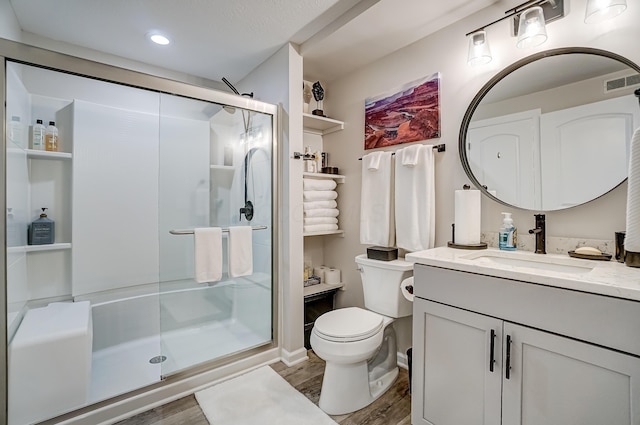 bathroom featuring vanity, wood finished floors, visible vents, a shower stall, and toilet