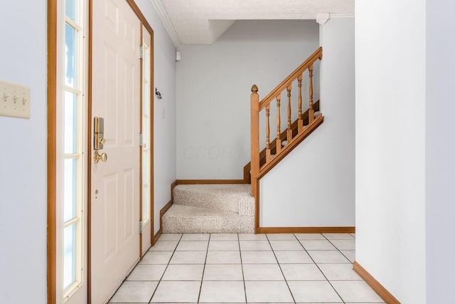 foyer with stairs, light tile patterned floors, baseboards, and a textured ceiling