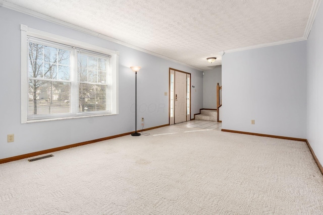 carpeted empty room featuring visible vents, a textured ceiling, crown molding, and stairway